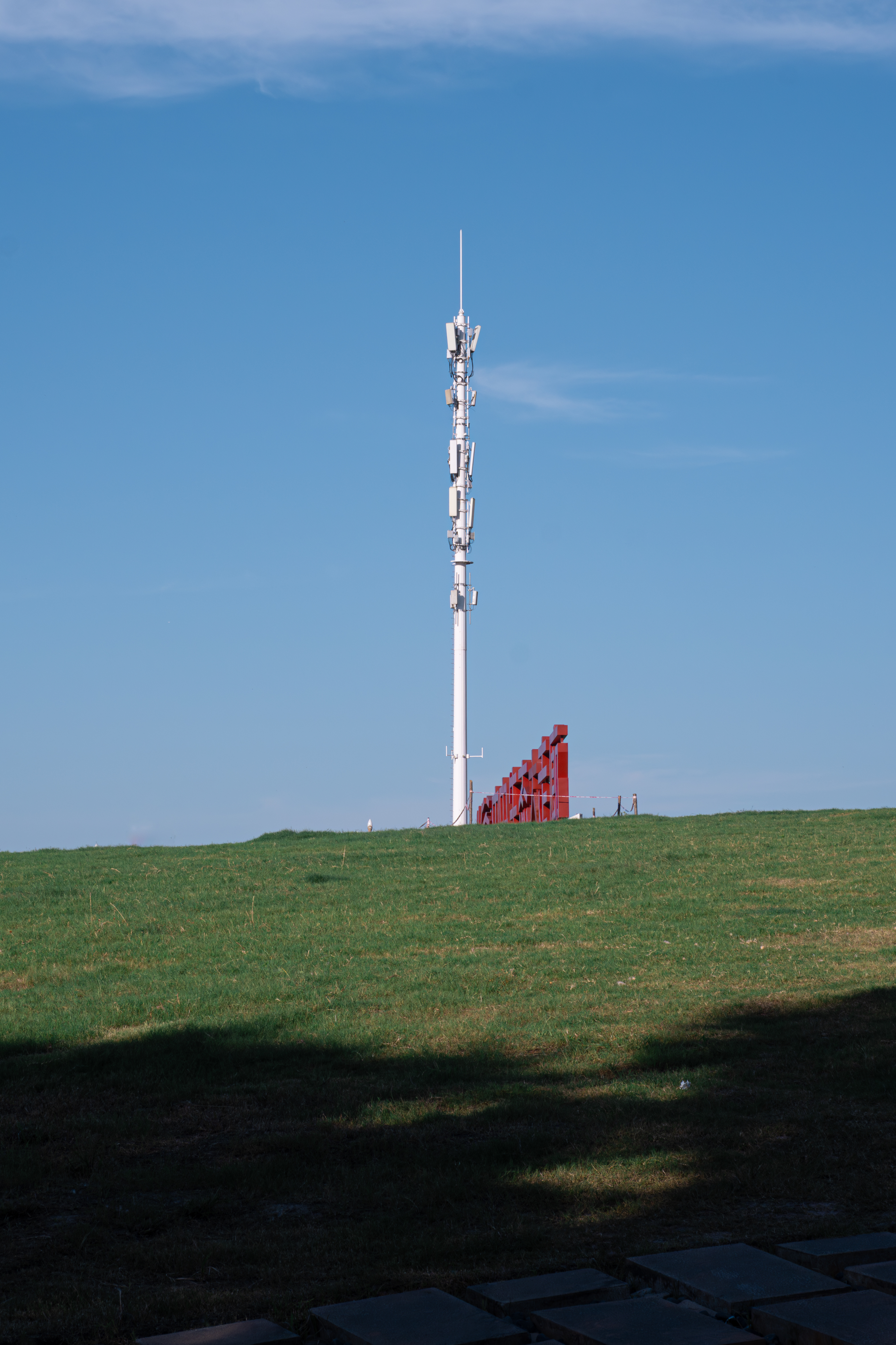 A cell tower standing on an open green hill